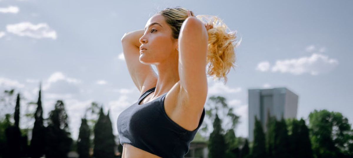 Fit woman in a black tank top enjoys a sunny workout outdoors in Ciudad de México, embracing wellness and healthy living.